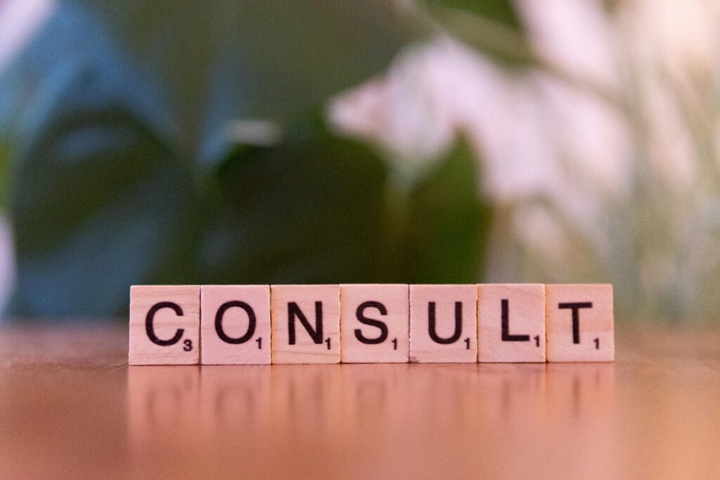 pexels photo 30945516 30945516 Scrabble tiles spelling 'CONSULT' on a wooden table with blurred background.